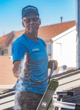 a man cleaning a gutter out on a residential home