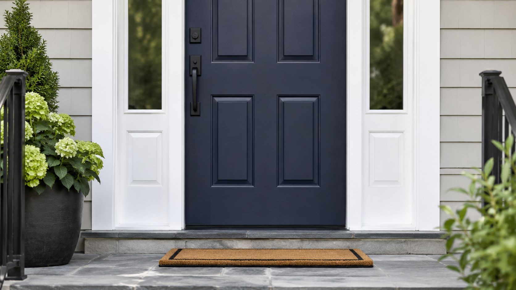A modern navy blue front door with a matching handle and an inviting welcome mat outside.