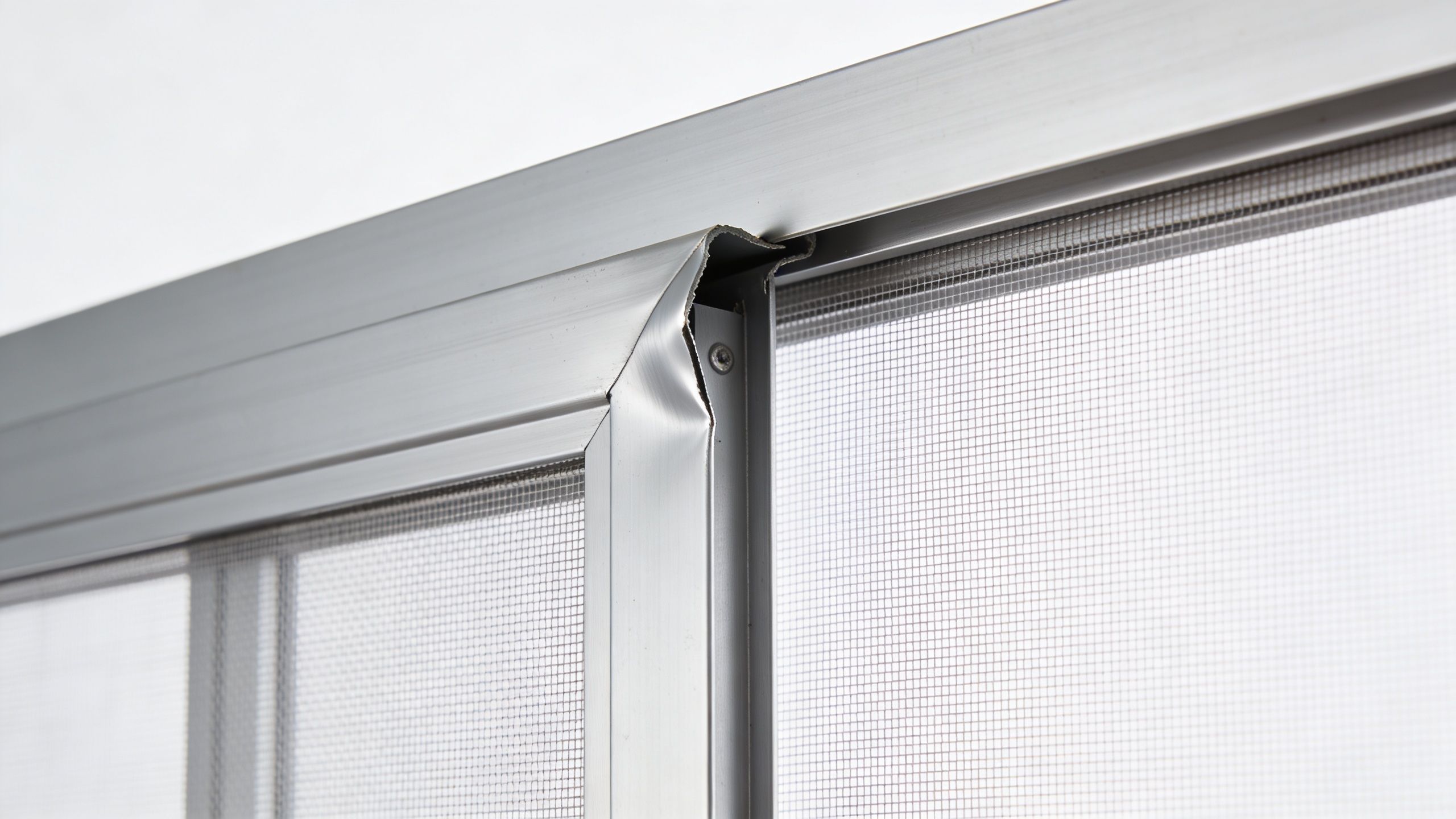 A close-up view of a bent aluminum window screen frame showing damage at the corner junction.