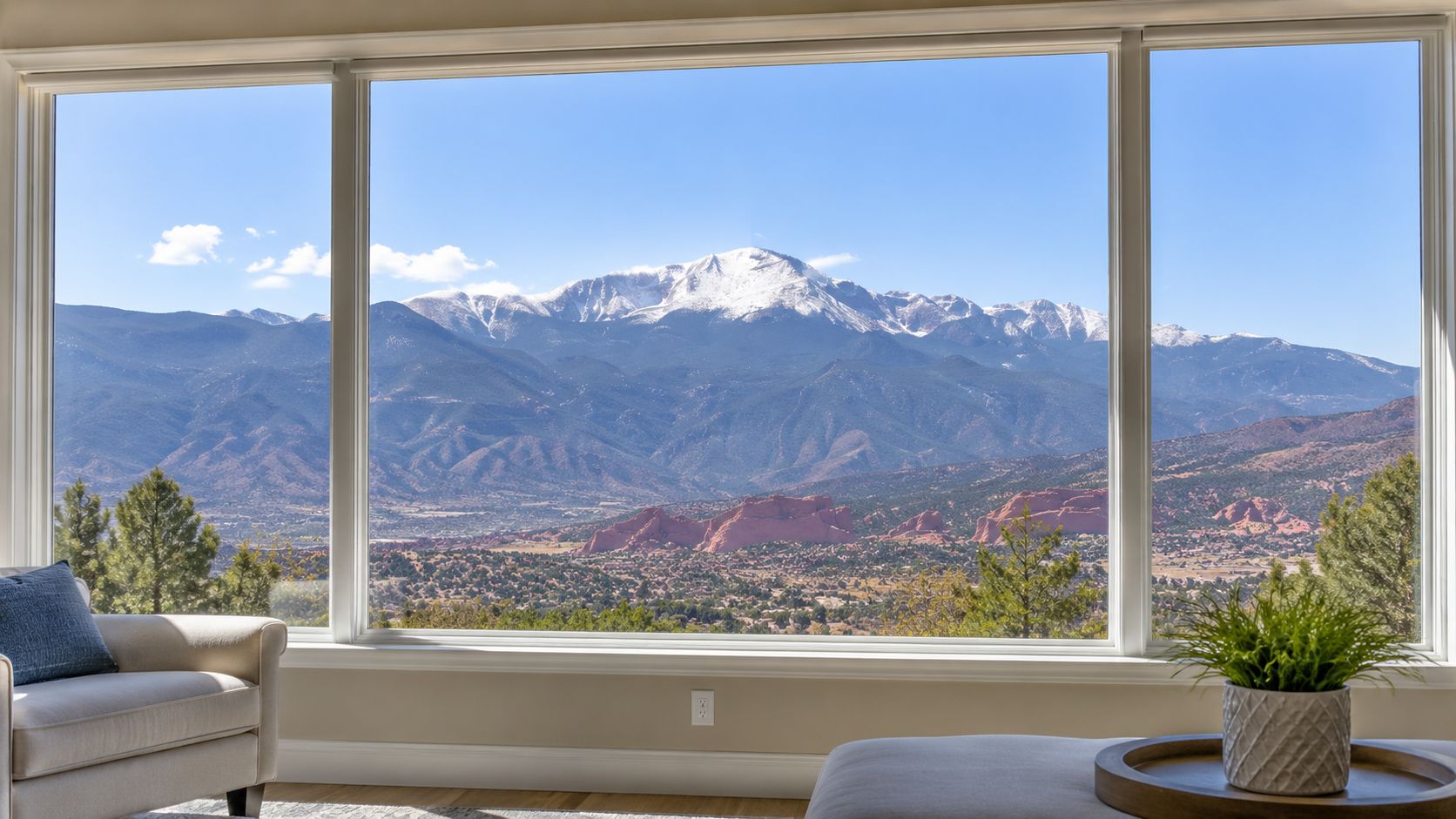 A scenic mountain view through a large clean picture window in a modern, comfortable living room.