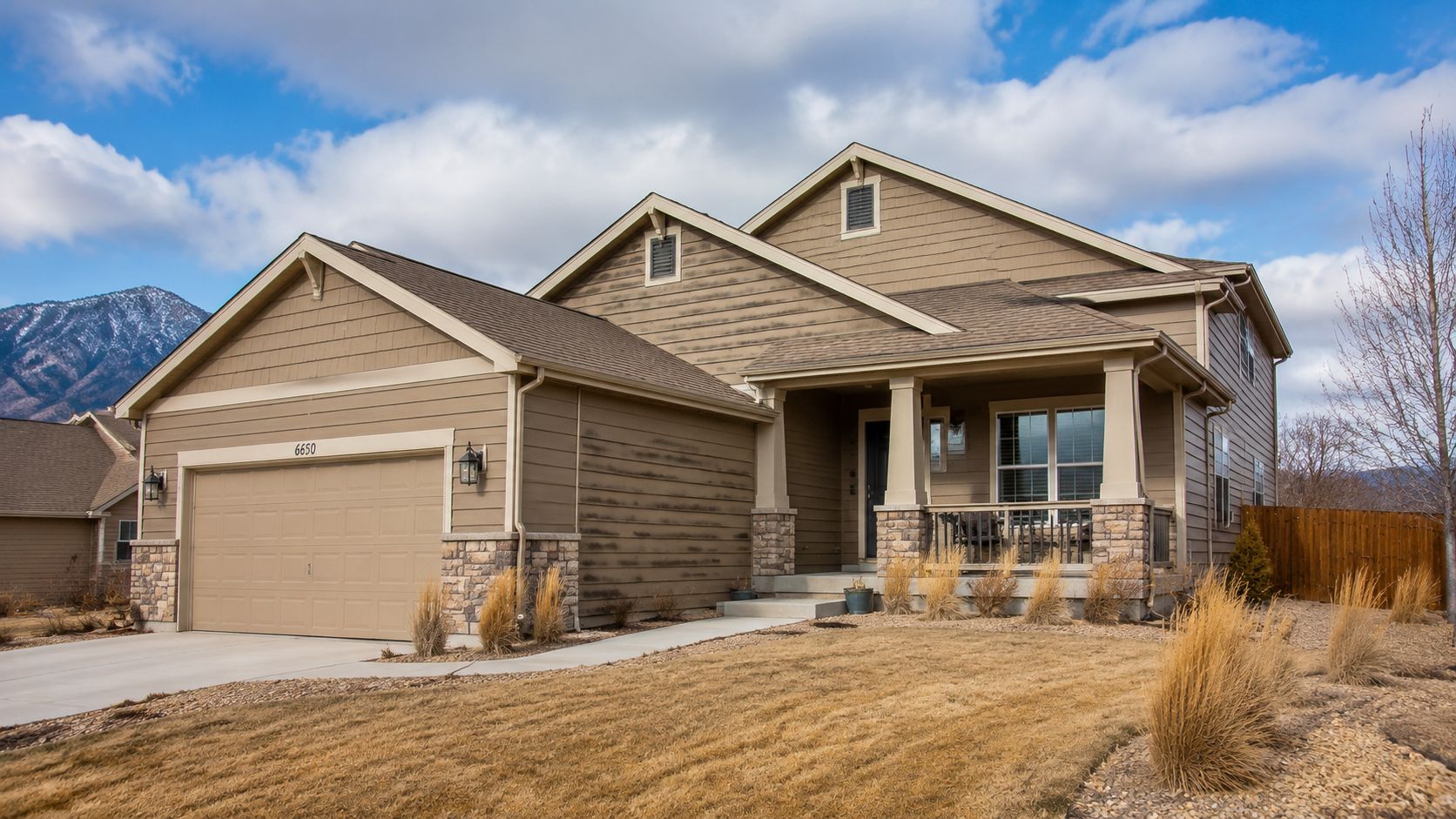 A tan suburban home with dirty dark streaks on the siding caused by mildew and organic growth.